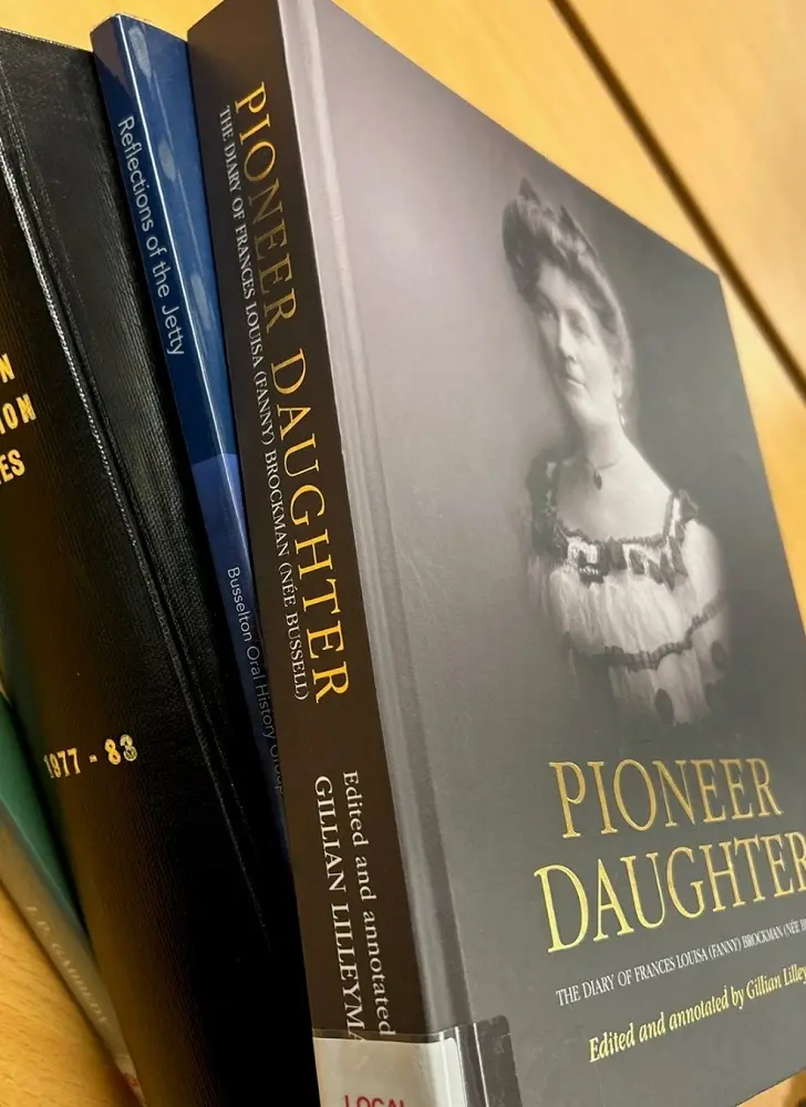 A stack of books, with a book titled Pioneer Daughter sitting on top.